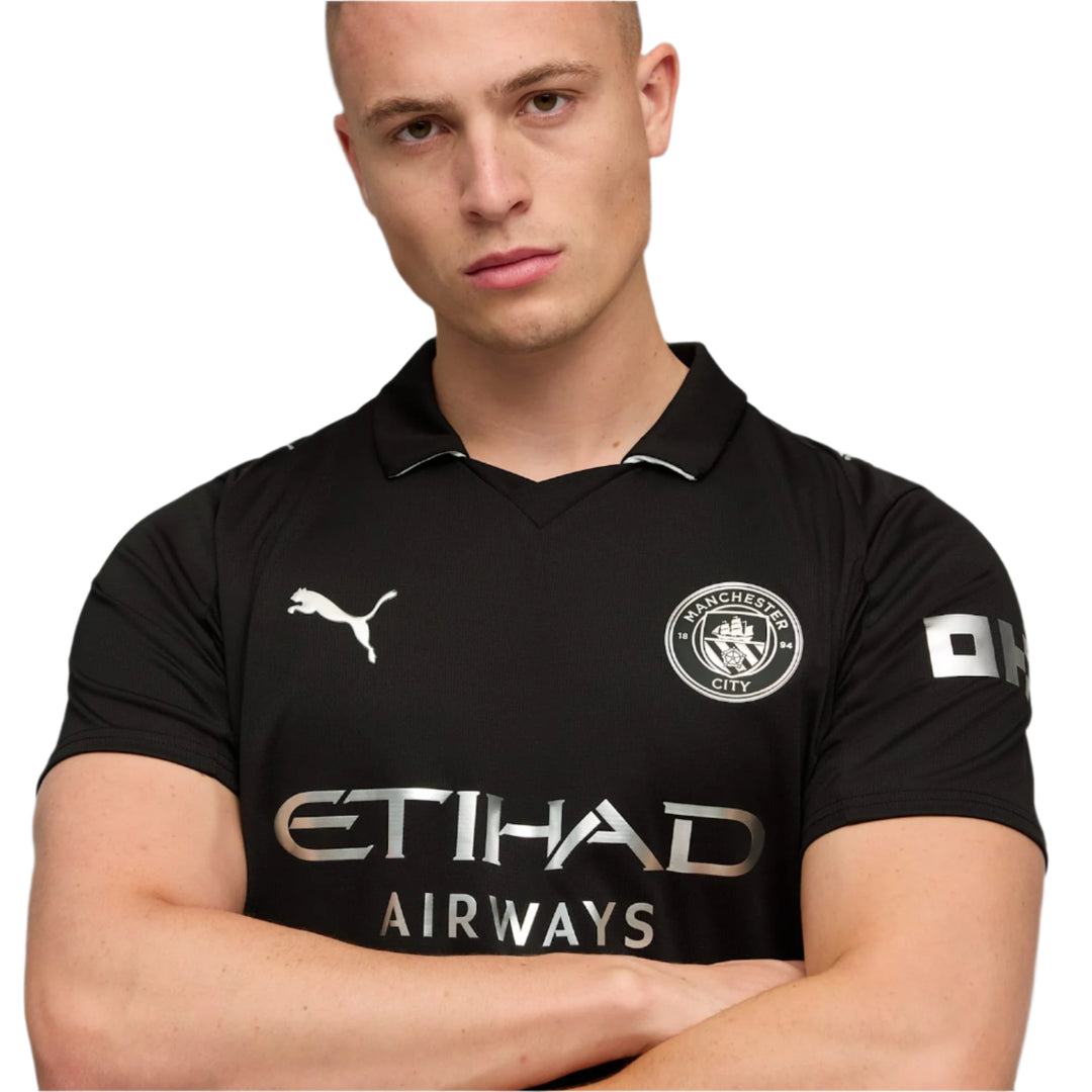 Man wearing a black 2025 20265 PUMA Manchester City sports jersey with Puma logo on a gray background