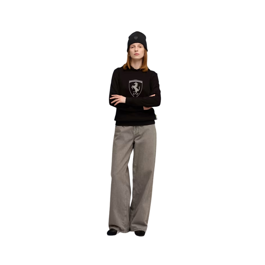 A woman wearing a Ferrari Formula 1 black hoodie Ferrari beanies with a logo and gray pants on a white background made by Puma 