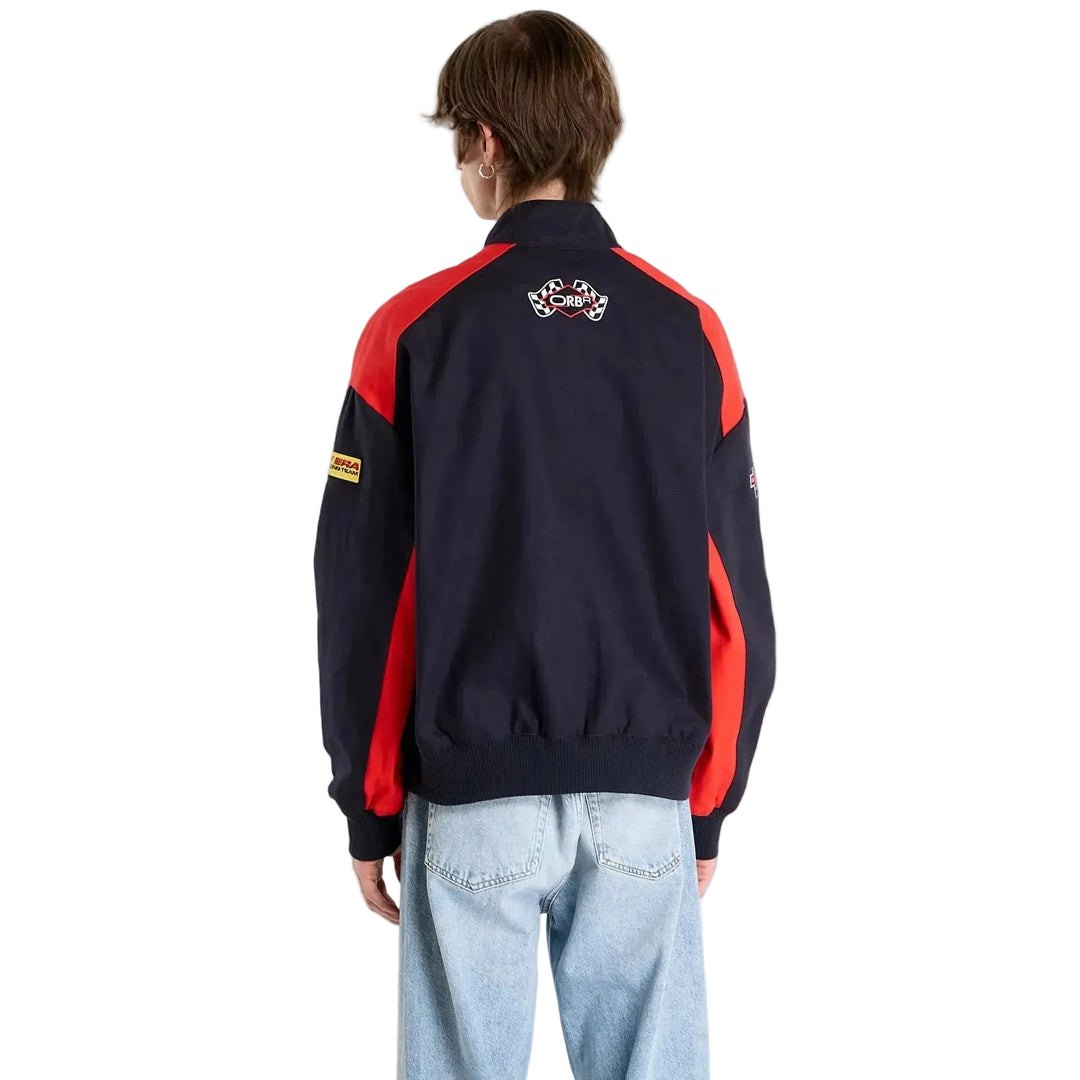 Rear view of a male model wearing the black Oracle Red Bull Racing New Era jacket with red shoulder panels and back emblem and checkered flags embroidered patch to the back with needled ORBR logo.