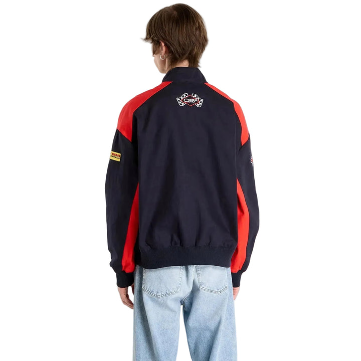Rear view of a male model wearing the black Oracle Red Bull Racing New Era jacket with red shoulder panels and back emblem and checkered flags embroidered patch to the back with needled ORBR logo.