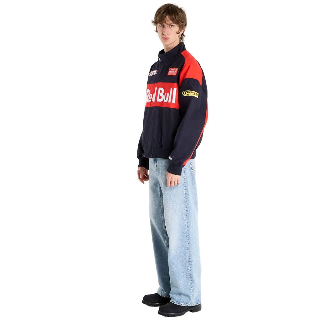 Side profile of a male model wearing the New Era Oracle Red Bull Racing black motorsport jacket with red sleeve detailing.