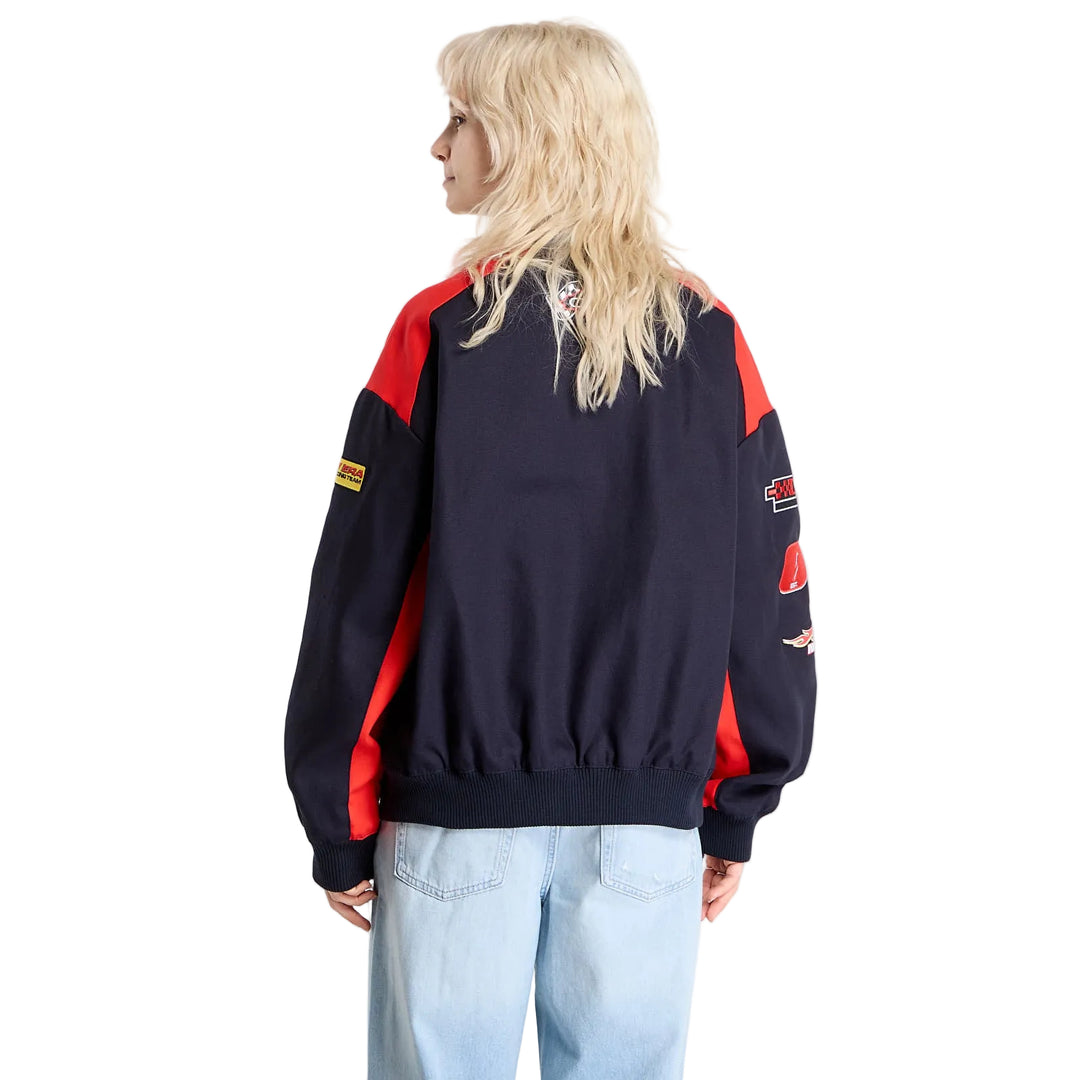 Rear view of a woman wearing the black New Era Red Bull Racing motorsport jacket with red shoulder and sleeve accents.