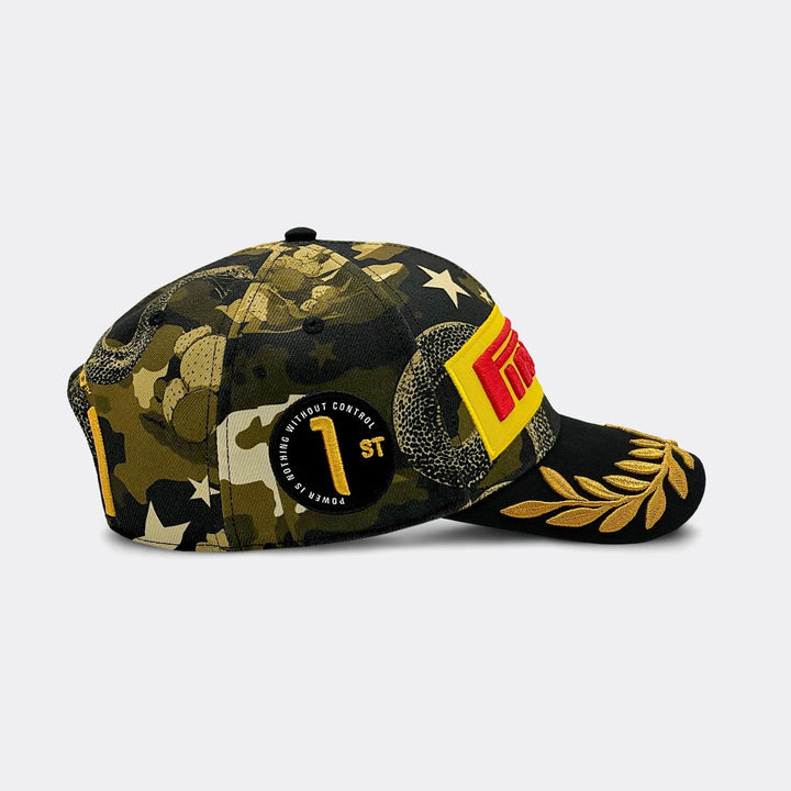 A structured Pirelli F1 2026 Austin GP Podium Cap – baseball cap featuring a dark green and black camouflage pattern with gold stars, a black circular patch with gold text, a yellow and red graphic on the side, and a gold laurel leaf design on the brim.