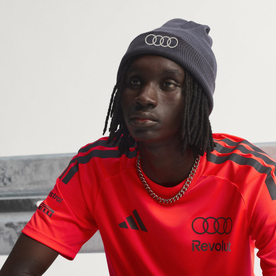 AUDI F1 FAN wearing a bright orange adidas x audi f1 team polyester orange t-shirt with Audi logos and a beanie with Audi logo