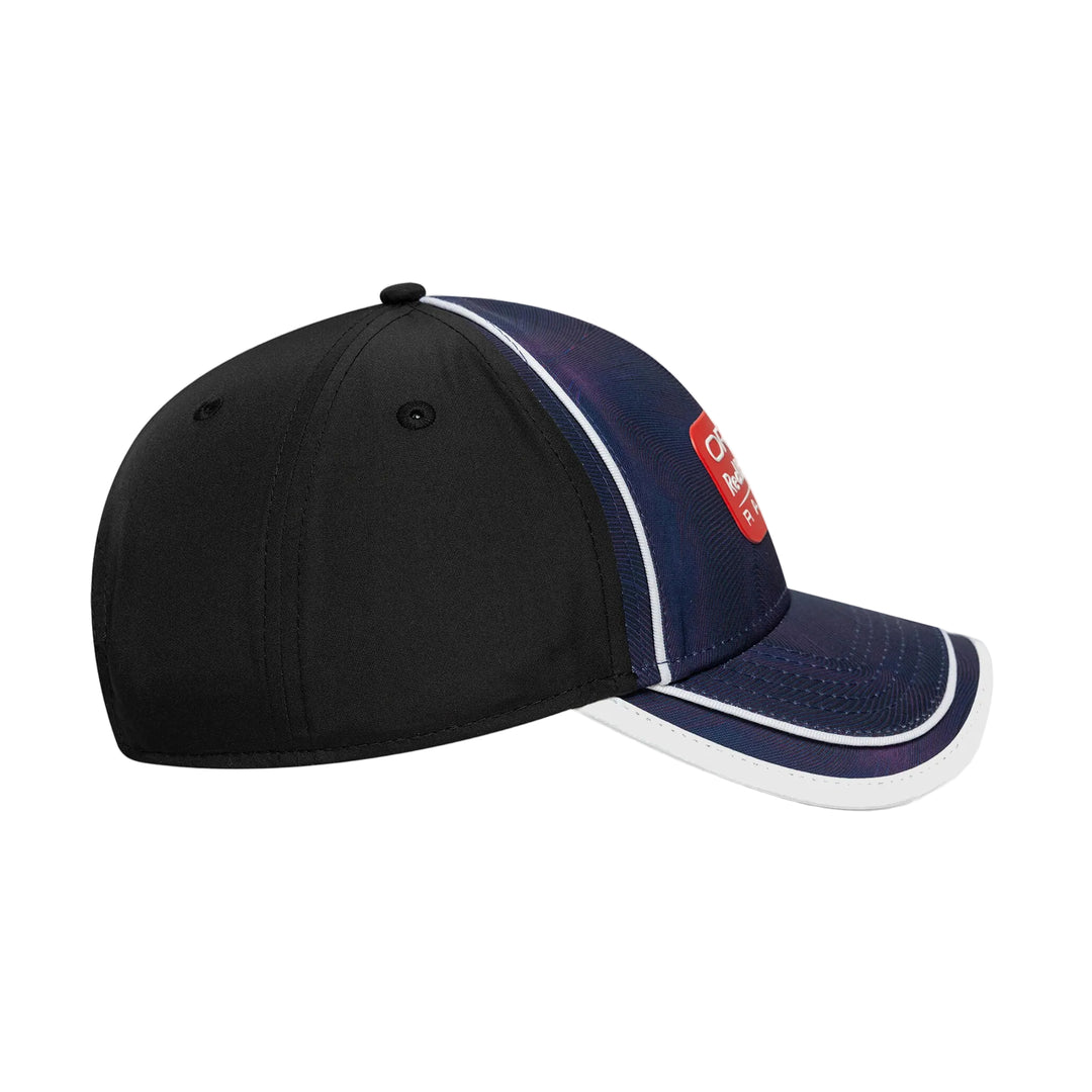 A baseball cap with a black front panel, navy blue mesh side panels, and a curved brim with white piping. A red rectangular patch on the side features white text.