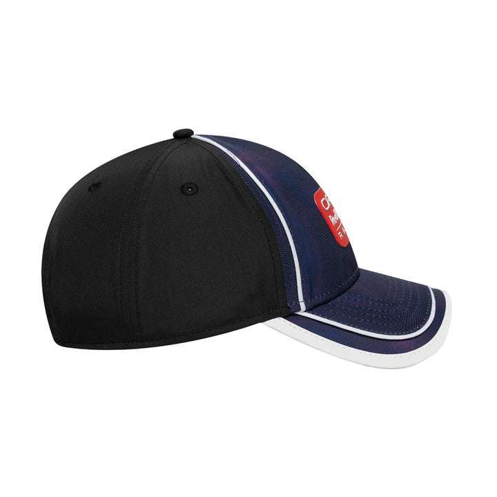 A baseball cap with a black front panel, navy blue mesh side panels, and a curved brim with white piping. A red rectangular patch on the side features white text.