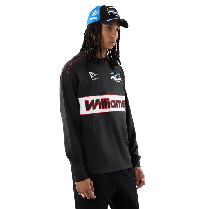 A model wearing a Premium 100% cotton Williams Racing 2026 Las Vegas Grand Prix limited edition apparel. 100% Genuine Williams F1 team long-sleeve shirt with a prominent white and red Williams logo across the chest, paired with a blue and black New Era cap, against a light gray studio background as well as a prominent Williams Racing Las Vegas GP limited edition hat.