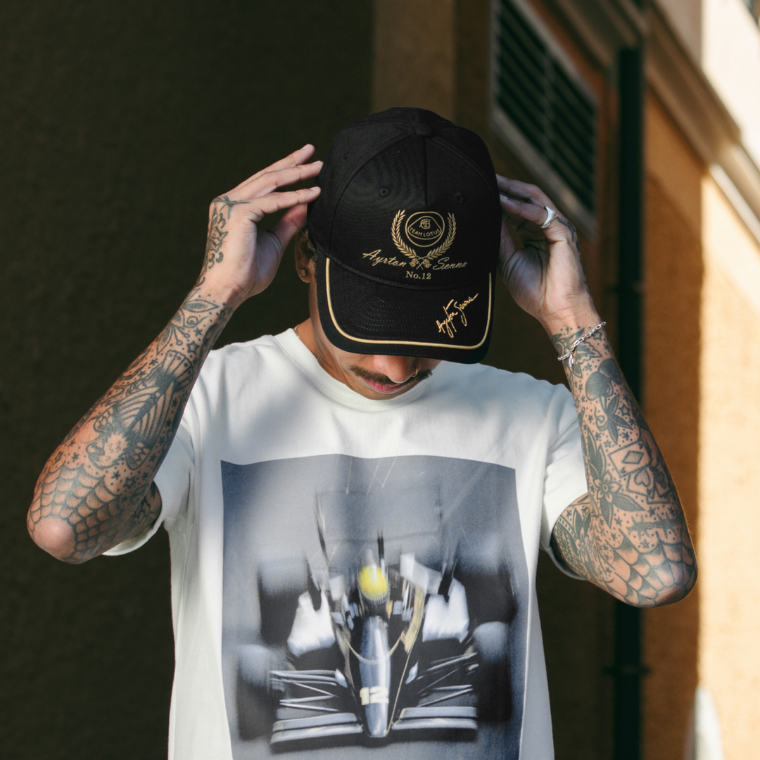 Ayrton Senna Team Lotus F1 black and gold cap shown in motorsport lifestyle setting