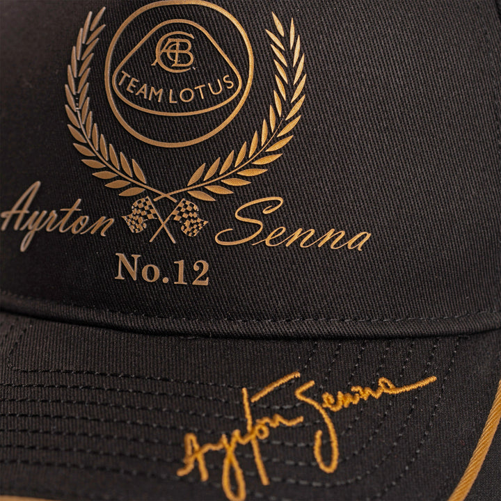 Ayrton Senna Team Lotus No. 12 cap close-up showing black and gold embroidered crest and signature