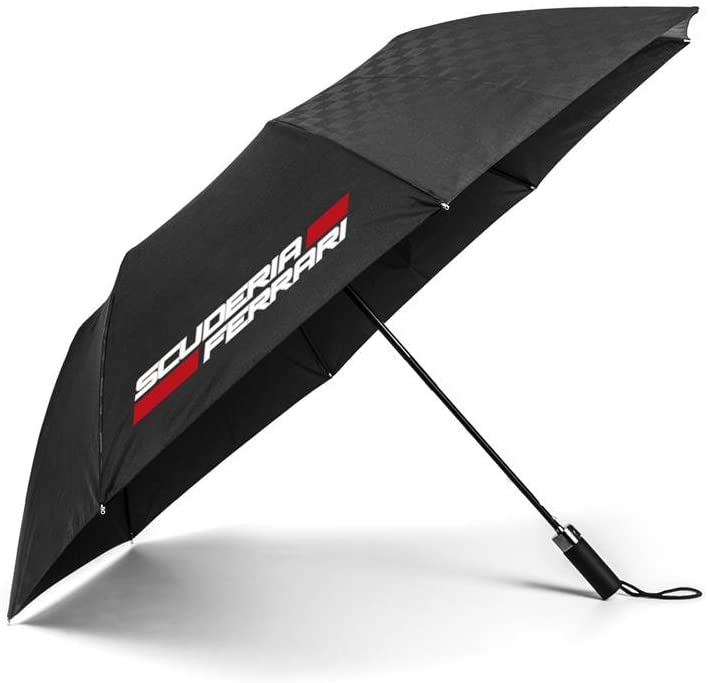 A compact, closed black Ferrari Formula 1 team umbrella with a matching protective sleeve, featuring the iconic yellow and black Ferrari Scuderia shield logo printed on both the umbrella canvas and the sleeve with retractable mechanism with a cord a fabric wrist strap. 